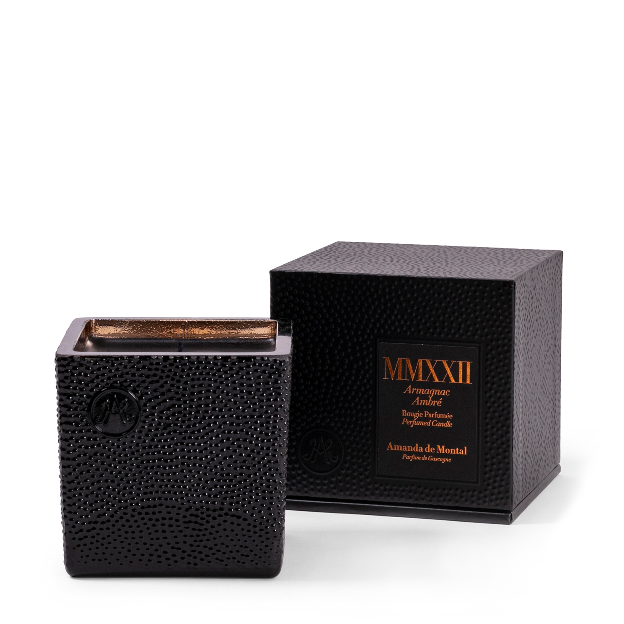 An artisanal black glass vessel, mouth-blown by master glassmakers, with thousands of bubbles and an amber mirror interior reflecting the twinkling light of the burning wick. Contains fragrances of cedar wood, tonka bean, gourmand prune, intense rose, and mysterious incense.