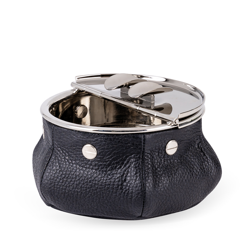 This windproof ashtray features a metal container that collects ashes, a metal lid containing the ashes, and cigar (or cigarette) holders underneath. Luxuriously covered in black leather, it makes a functional and decorative piece for any space.