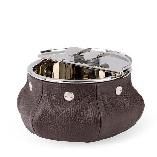 This windproof ashtray features a metal container that collects ashes, a metal lid containing the ashes, and cigar (or cigarette) holders underneath. Luxuriously covered in dark brown leather, it makes a functional and decorative piece for any space.