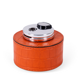 This table lighter features a handcrafted rounded wood base, luxuriously covered in orange embossed leather, making it a vibrant detail with an expressive texture.