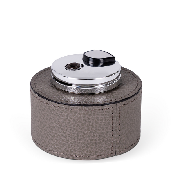 This table lighter features a handcrafted rounded wood base, luxuriously covered in grey embossed leather, making it a classic detail with an expressive texture.