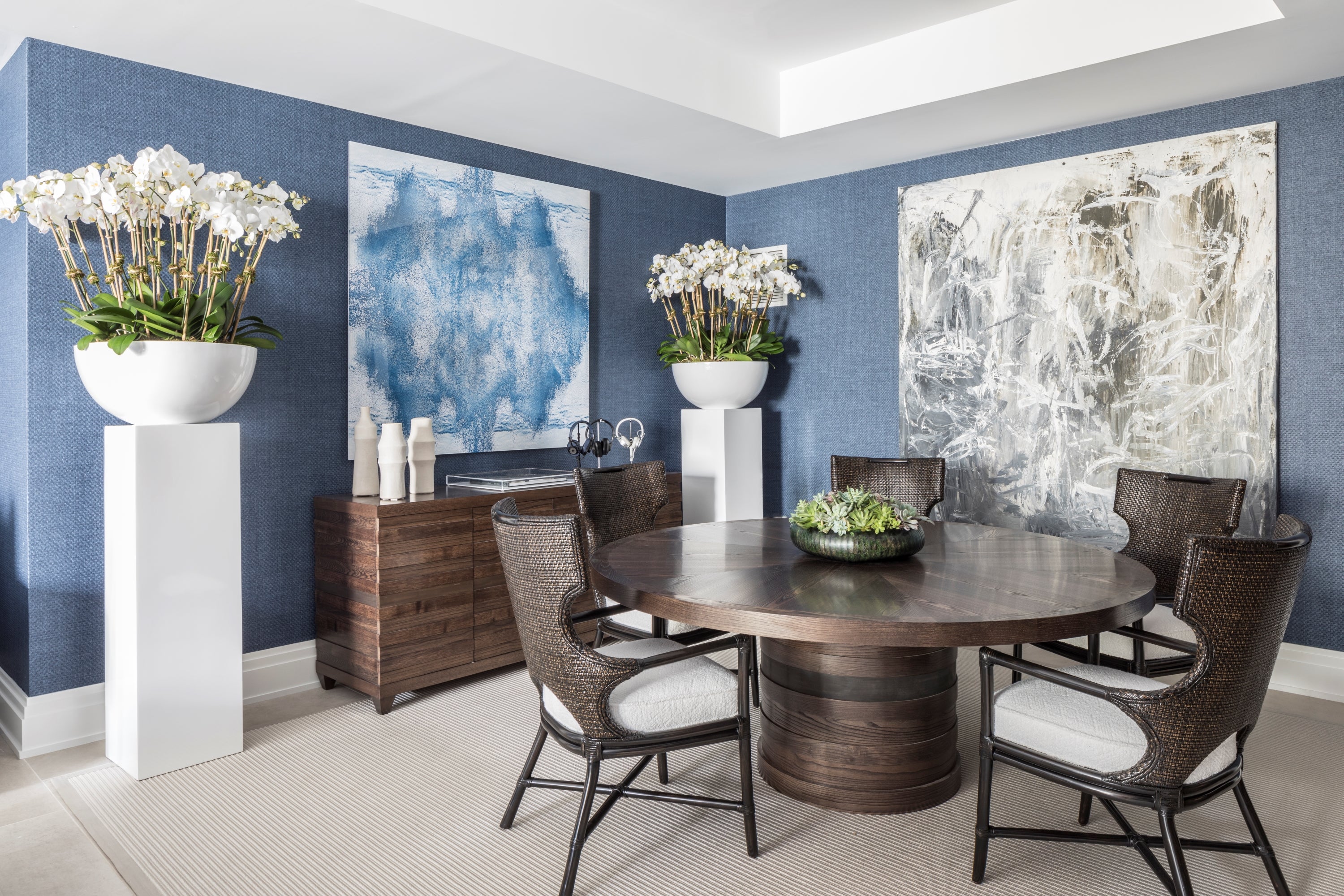 Dining room with a round wooden table, chairs, and abstract wall art.