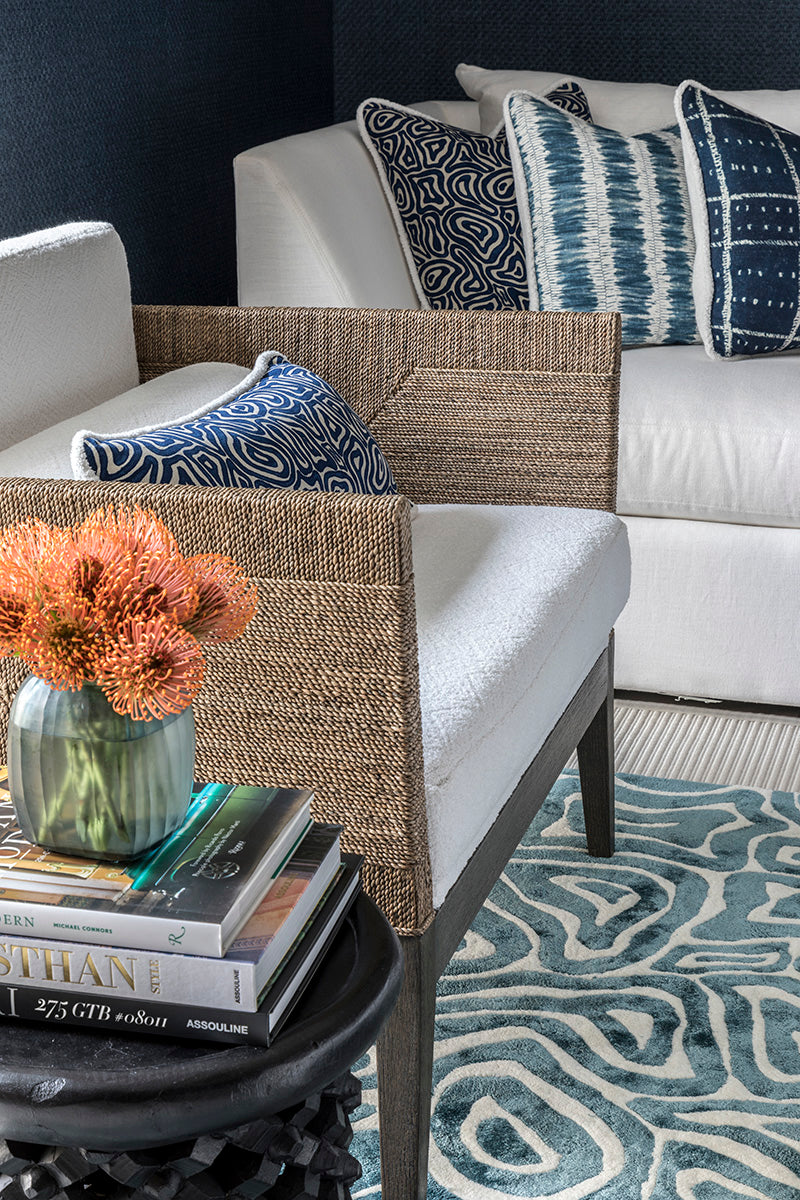 Living room with a wicker chair, white sofa, and patterned rug.