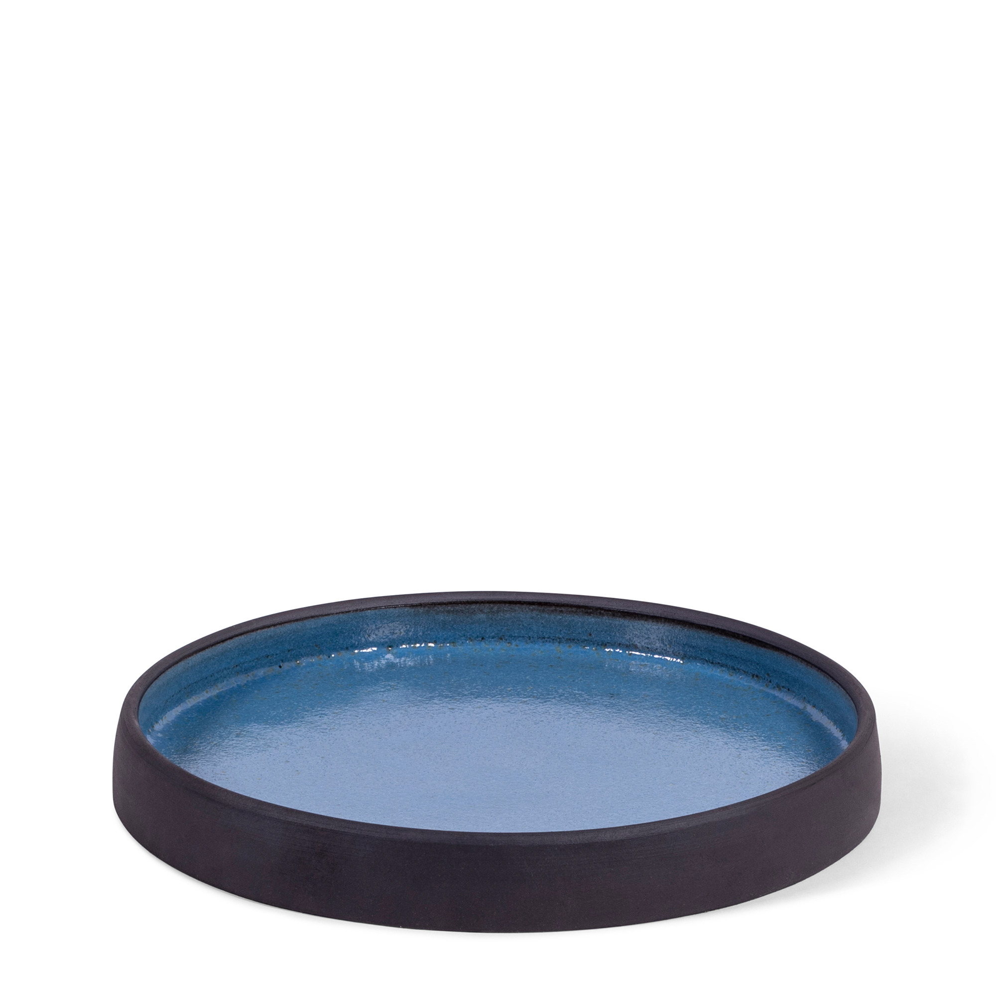 Artisanal dinner plate with a high-lipped edge, combining raw blackware with a soft delft blue glaze. Each piece features unique natural variations.